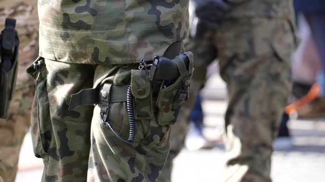 Anonymous unrecognizable professional soldier standing on the street in traditional generic camo uniform. Legs closeup, gun in holster. War, warfare, professional army, infantry concept, one person
