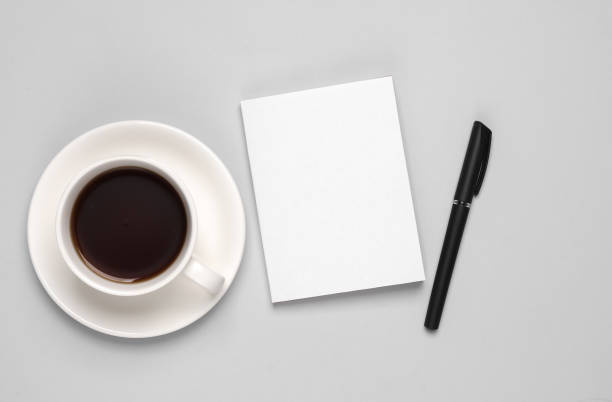 istock Coffee cup and book or notepad mockup with white cover, pen on gray background. Template for design 1514496713