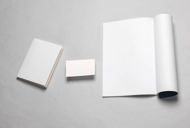 istock Creative template for design. Mockup of an open magazine with white pages, empty business card, book, or notebook with white cover on gray background. Top view 1514497241