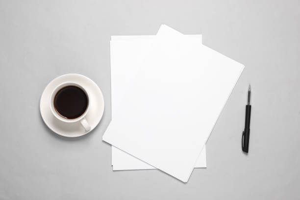 istock White blank sheets of a4 paper size or documents mockup with pen and coffee cup on a gray background. Template for design. Top view. Copy space 1514497760