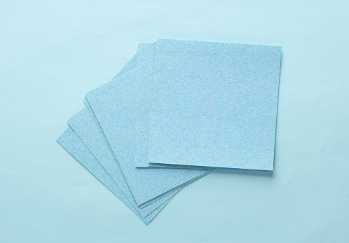 Stack of blue square memo sheet of papers on blue background. Top view