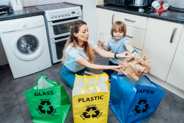 istock Mother is teaching kid how to recycle help the boy aware environmental importance - mom educates son sort garbage into different bins on kitchen. Family sorting garbage at home. Concept of recycling. 1514502329