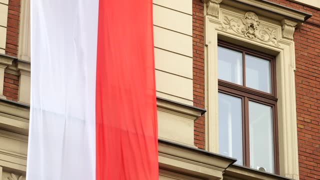 Large Polish flag hanging from the side of a building, Poland, Polish patriotism concept, national symbols, Independence Day parade. Object closeup, simple symbol, nobody, no people