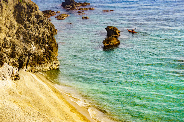 Rocky sea shore with person kayaking, Andalucia Spain.