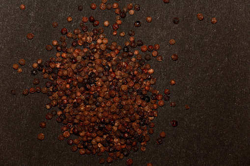 Black peppercorn table top view isolated on plain black background.