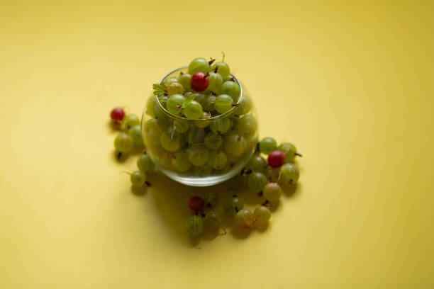 Gooseberries in a transparent jar on a yellow background