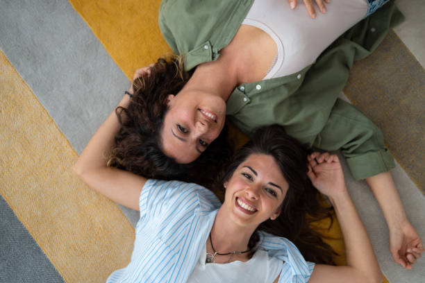 istock Two smiling young women looking at camera while lying on the carpet at home 1514669645