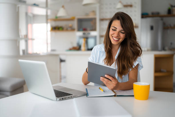 female business person using digital tablet and laptop e-learning or remote working at home office - evde çalışma stok fotoğraflar ve resimler