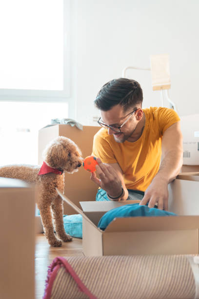 Young man unpacking cardboard boxes with his dog friend
