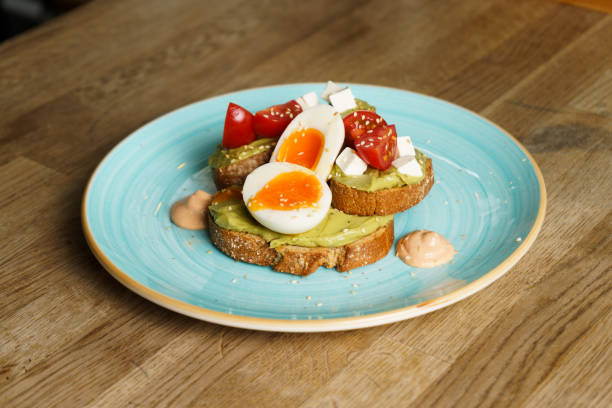 istock Avocado toast with guacamole, soft boiled egg, cream cheese and tomatoes on a plate 1514710152