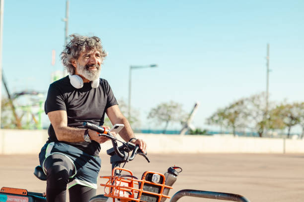 Active senior man is sports clothes using bicycle sharing system in the city
