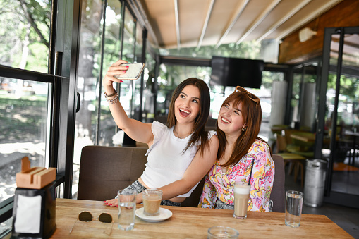 Two Smiling Females Taking Selfie During Coffee Time