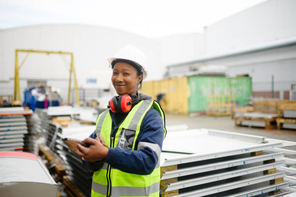 istock Smiling Female Construction Worker with smartphone standing in a warehouse yard 1514719752