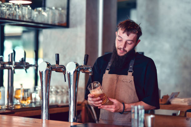 istock Bearded Bartender Holding Beer Pint With Care While Pouring 1514726702