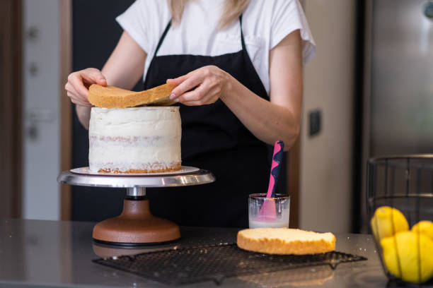 istock Professional confectioner in black apron connecting cake layers smeared with cream 1514727250