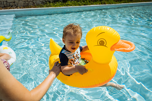 Cheerful baby boy learning to swim