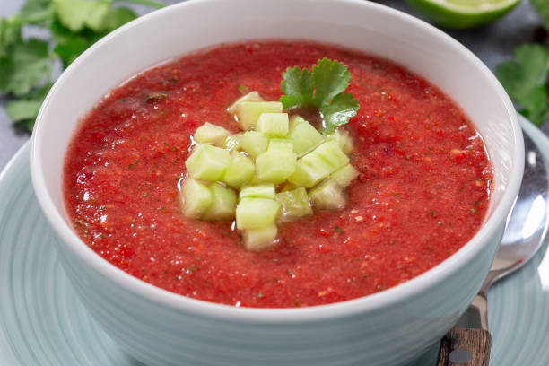 Gazpacho soup garnished with cucumber and cilantro, in bowl, horizontal closeup stock photo