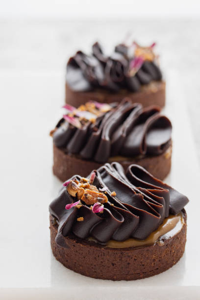 istock Chocolate tartlets decorated with dark chocolate ganache on a white background. 1514757677