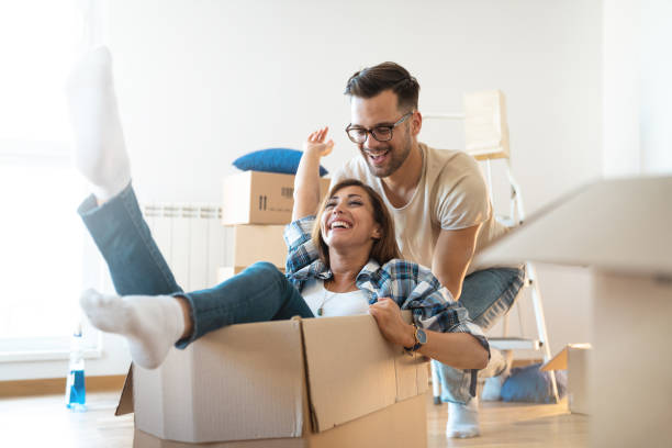 Photo of happy smiling couple going for a magic box ride in their new home surrounded by boxes, ladders and cleaning stuff Photo of happy smiling couple going for a magic box ride in their new home surrounded by boxes, ladders and cleaning stuff. fresh start stock pictures, royalty-free photos & images