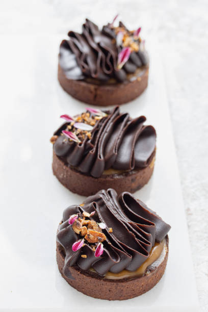 istock Chocolate tartlets decorated with dark chocolate ganache. Composition with multiple tartlet 1514758214