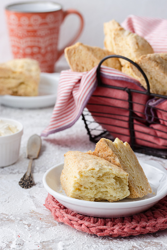 Basket with cheese scones, table set for afternoon tea with cheese scones. Scones in a basket with cloth napkin on a served table for breakfast