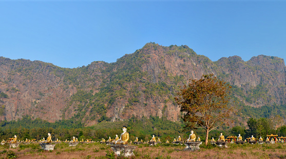 Panoramic view of the Garden of One Thousand Buddhas in Hpa-An, Myanmar. Mount Zwegabbin in the rays of the setting sun on the background.