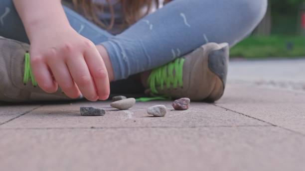 Caucasian Girl Mastering Dexterity Game of Jackstones Scatter Jacks Knucklebones using Small Rocks Caucasian Girl Mastering Dexterity Game of Jackstones Scatter Jacks Knucklebones using Small Rocks dibs stock pictures, royalty-free photos & images