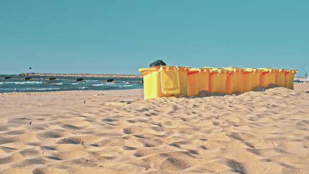 istock Row of Plastic Garbage Bins Deployed on Seashore Beach Sand 1514792801