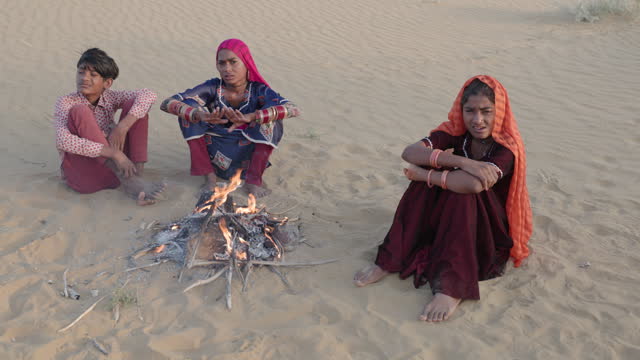 Indian kids setting up bonfire on sand dune