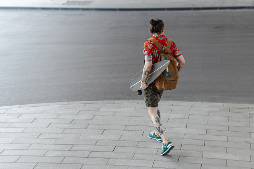 Rear view of a male skateboarder with a tattooed body on the move
