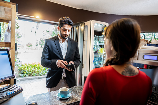 Businessman reaching for his wallet to pay for the coffee he drank at the coffee shop