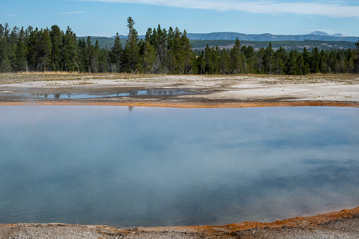 Natural scene of boilng flowing water from geyser basin with white smoke inside dangerous hot zone in Yellowstone national park, Wyoming, USA.