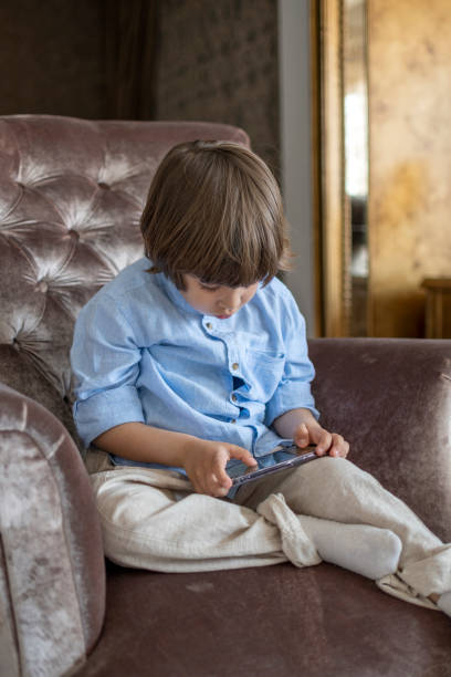 przystojny mały chłopiec korzystający z telefonu komórkowego w pomieszczeniu - human hand holding iphone iphone 5 zdjęcia i obrazy z banku zdjęć