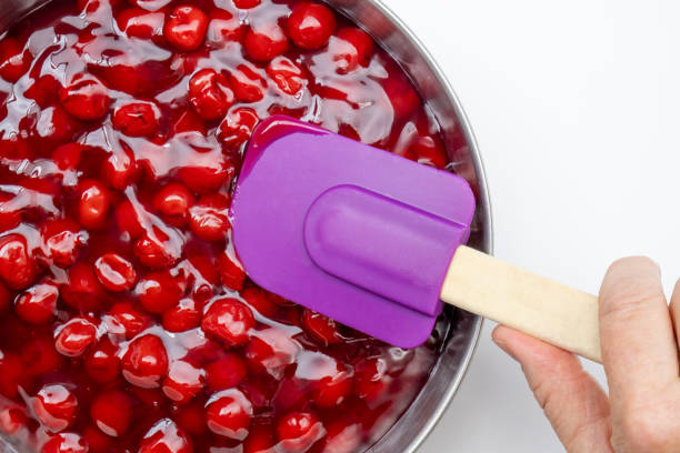 istock A hand holding a purple rubber spatula spreading cherry pie filling in a silver pan. Clean white table top flay lay 1514953020