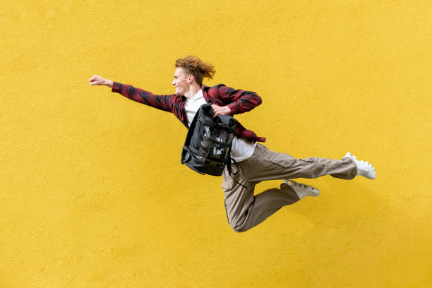 istock young guy student with backpack flies forward and hurries to study, man jumps and runs in the air 1514980623