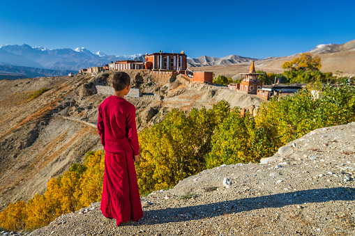 Novice Tibetan buddhist monks looking at the view in Tsarang village in Upper Mustang. Tsarang monastery on the background. Mustang region is the former Kingdom of Lo and now part of Nepal,  in the north-central part of that country, bordering the People's Republic of China on the Tibetan plateau between the Nepalese provinces of Dolpo and Manang.