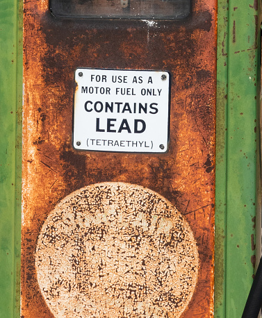 Detail of an old gasoline pump with lead warning.