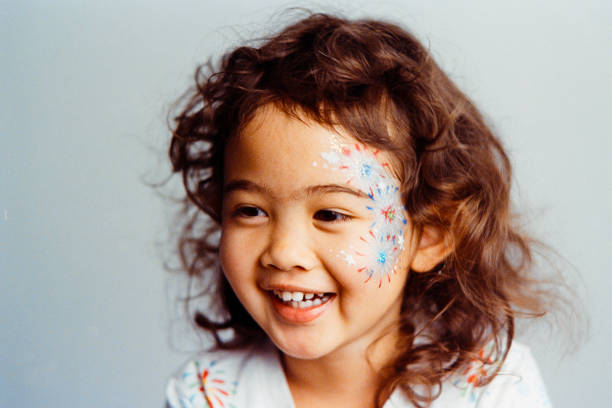 A three year old multiracial girl with celebration face paint. Photographed on 35mm film and digitally scanned.