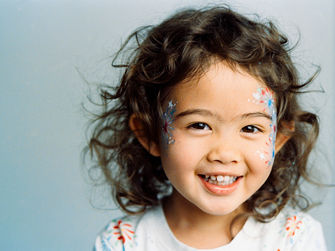 A three year old multiracial girl with celebration face paint. Photographed on 35mm film and digitally scanned.