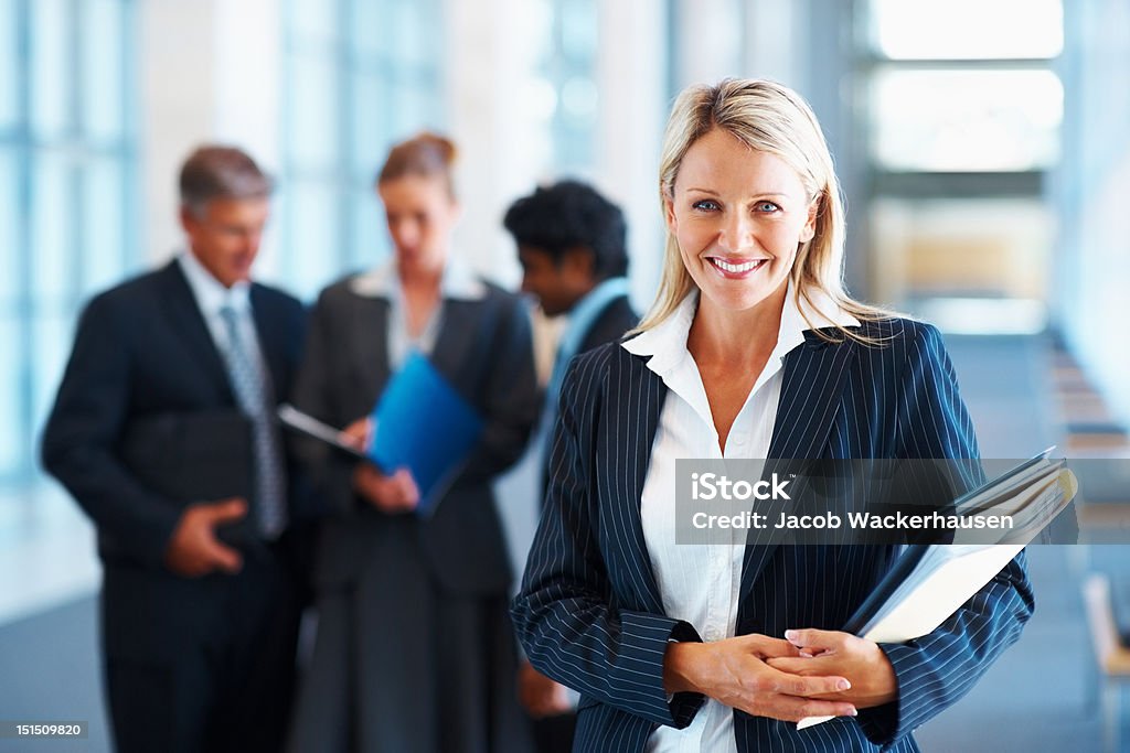 Happy businesswoman with colleagues in the background Blond Hair Stock Photo