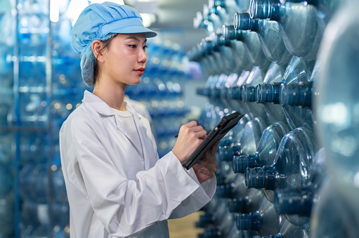 Immerse yourself in the world of precision and expertise as a professional nutritionist worker in lab coats working in the modern manufacturing facility. Using digital tablet to check artwork and analyze, inspect every aspect of plastic bottle.