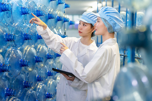 Enter the world of meticulous inspection in the water bottle factory where expertise, teamwork and attention to detail converge. Nutritionist worker woman inspectors as ensure purity and quality of bottle before filling water. Immerse the harmonious blend of technology