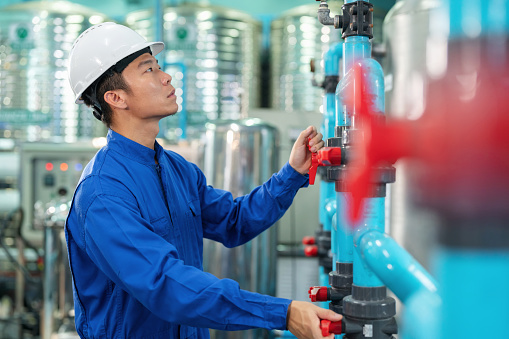 Enter the realm of engineering brilliance as a man in safety suit inspects the valve with confidence and expertise in the water factory. Meticulous scrutiny guarantees optimal performance. Immerse of industrial engineering and the seamless fusion of human skill and machinery