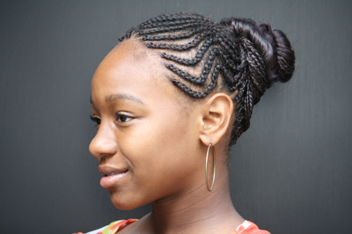 African American teen girl headshot, hair in braids wearing flower patterned shirt. Dark gray background