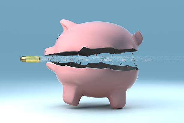 Bullet shooting through a pink piggy bank  stock photo