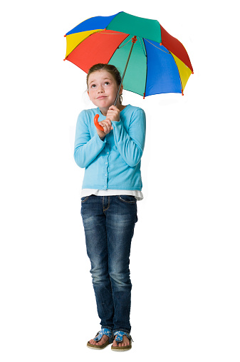 Pretty young girl casually dressed sheltering under a colourful umbrella. Cut-out image. Please look at my portfolio for more images with this model against a white background.