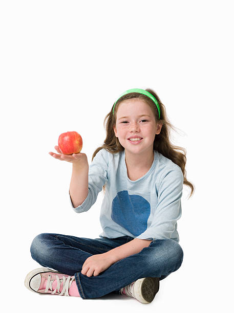 美しい若い少女、座る胡坐赤いリンゴを保持 - eight legged ストックフォトと画像