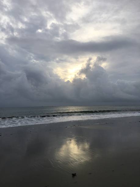 istock The sun dramatically breaks through a gray cloudbank and reflects on the silver sand at the beach 1515164125