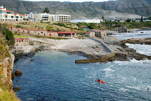 Hermanus Old Harbour Picture of two people in a kayak rowing toward Hermanus Old Harbor, Western Cape, South Africa hermanus stock pictures, royalty-free photos & images
