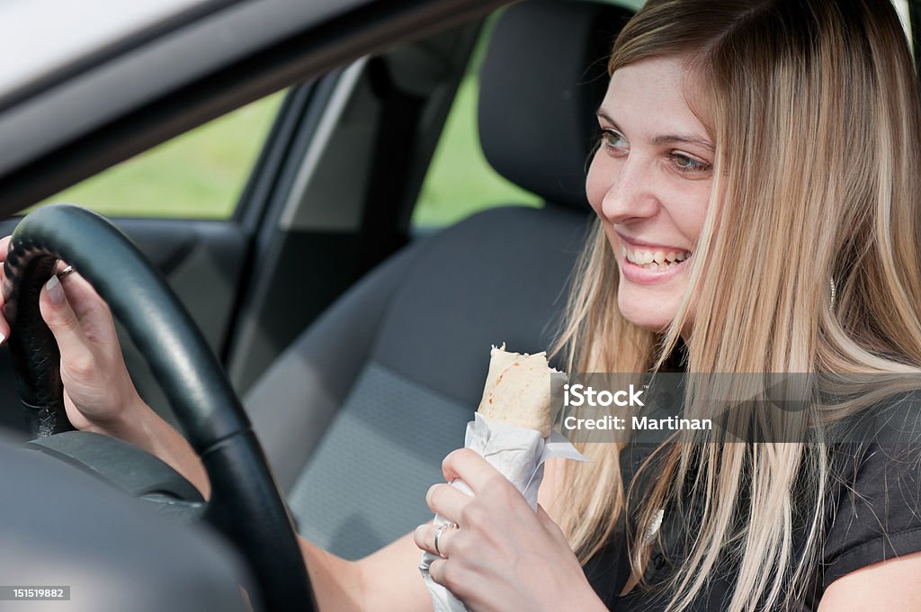 Retrato de joven mujer comiendo al conducir coches - Foto de stock de Coche libre de derechos